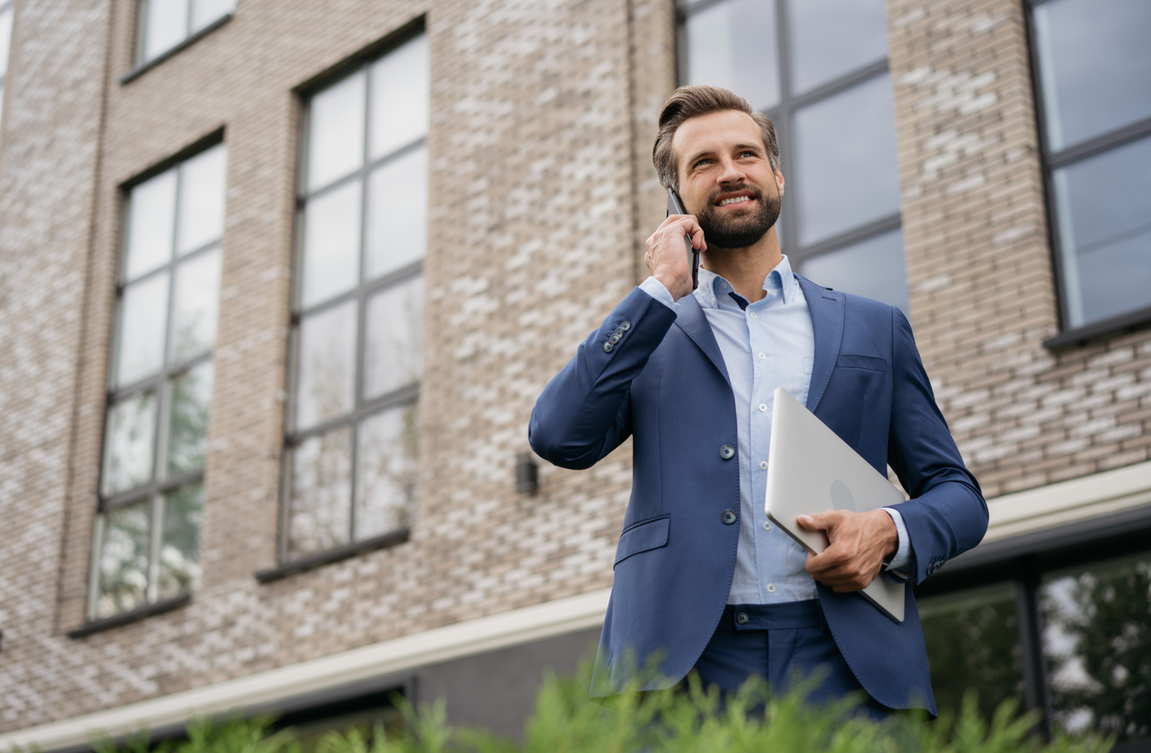 real estate investor talking on phone in front of building