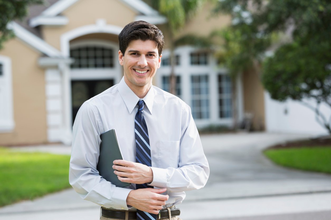 real estate investor holding papers in front of house