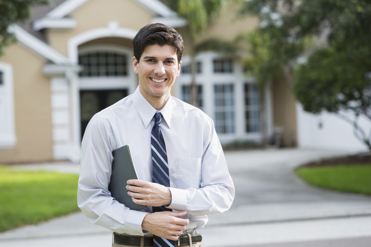 real estate investor holding papers in front of house